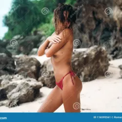 Gorgeous Young Woman in a Red Bikini without Bra on a White Sand Beach Covering Her Breast with Hand. Summer Vacation Stock Image