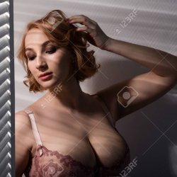 A Beautiful Young Woman With Very Large Natural Breasts Is Standing By The Window With Shutters. A Girl In Pink Lace Shows A Beautiful Figure Next To A White Screen. Huge Female